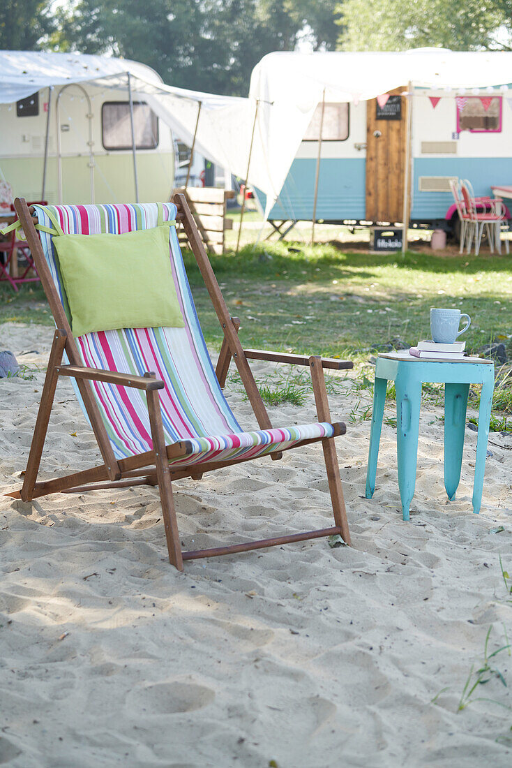 Klappstuhl mit bunt gestreiftem Stoffbezug und Beistelltisch auf Campingplatz