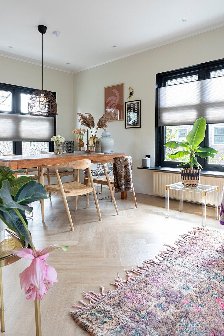 Bright dining room with wooden dining table, chairs and indoor plants