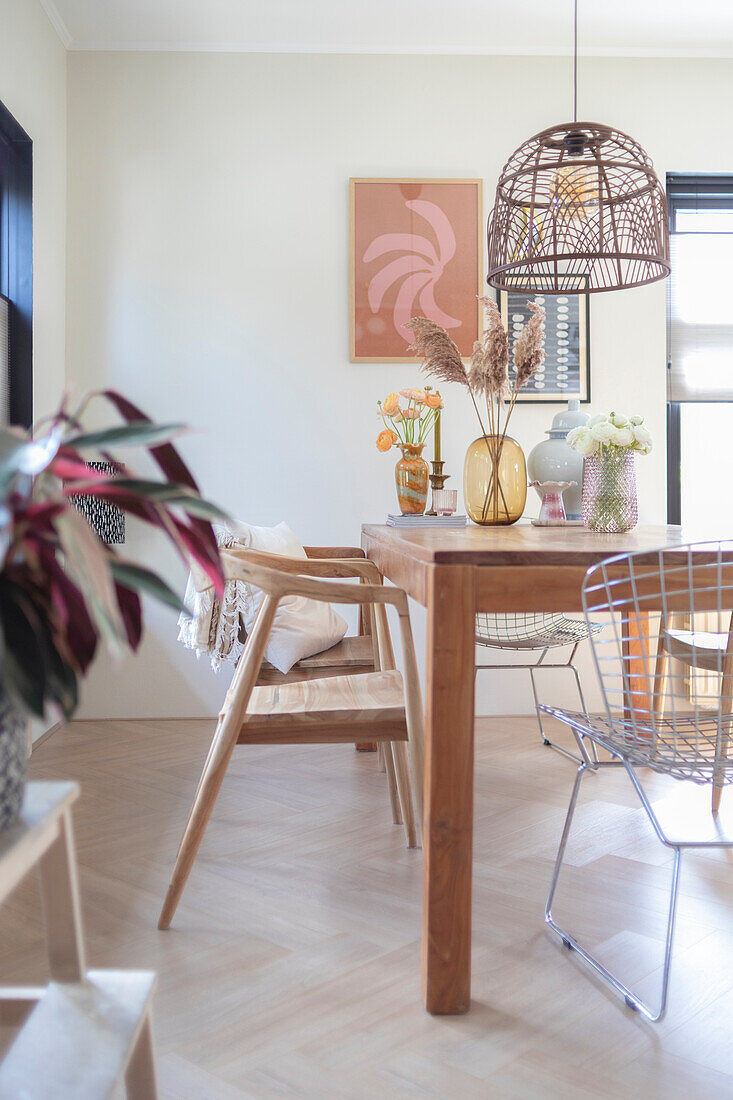 Dining room with wooden table, wire chairs and wicker lamp