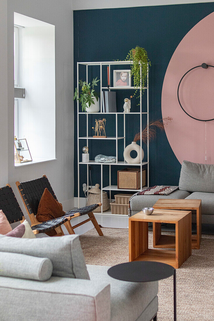 Modern living room with white shelving, grey sofa and light pink wall decor