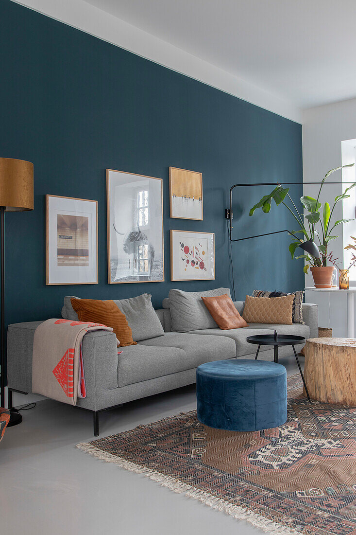 Graues Sofa und blauer Hocker im modern dekorierten Wohnzimmer mit Bilderwand