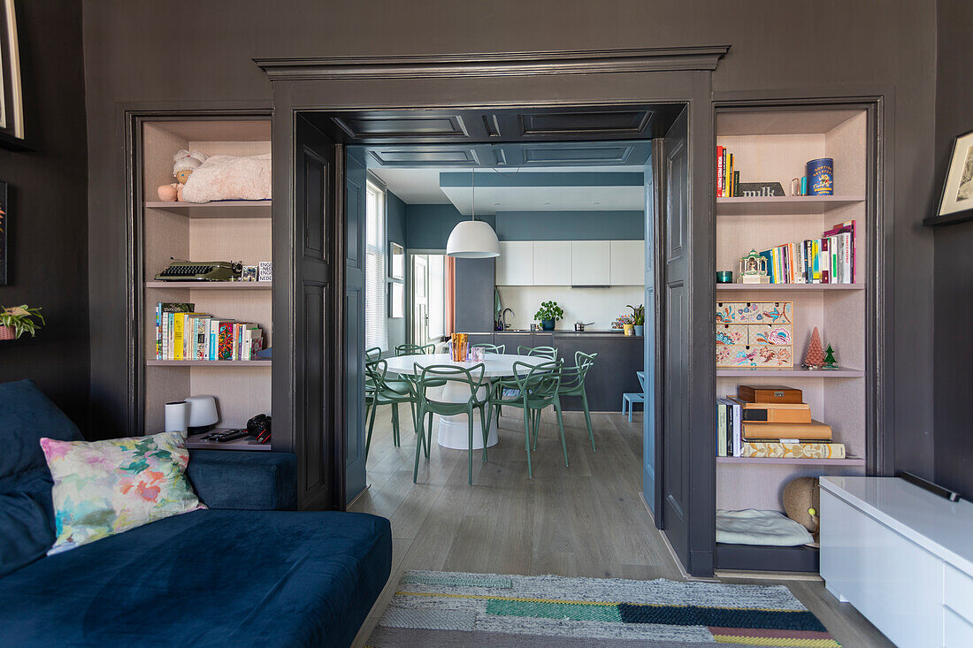 Dark painted living room with view of modern kitchen and built-in shelves