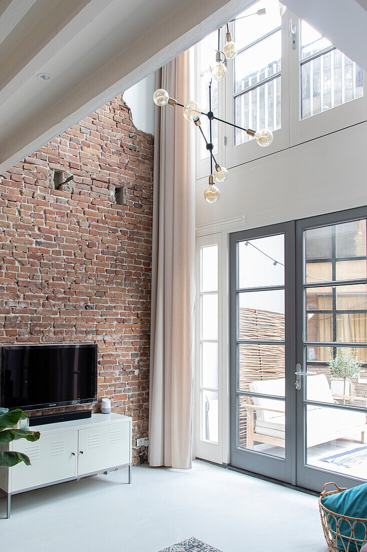 Living room with brick wall, patio door and modern pendant light