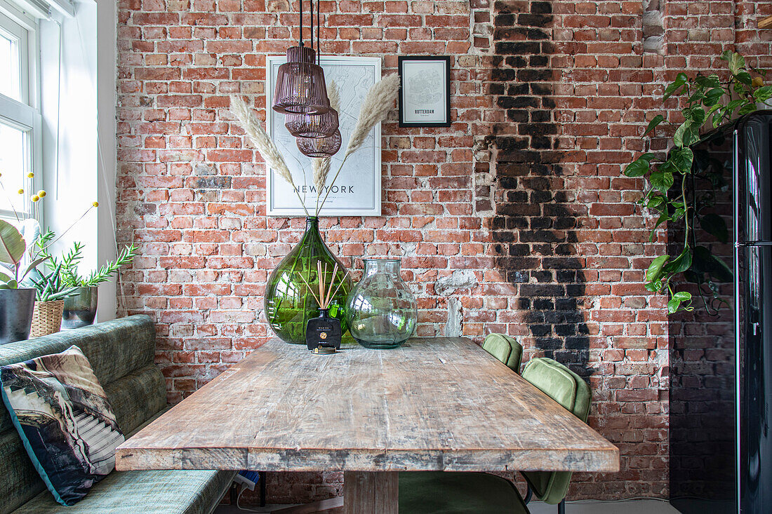 Dining area with rustic wooden table and brick wall, decoration with vases and plants