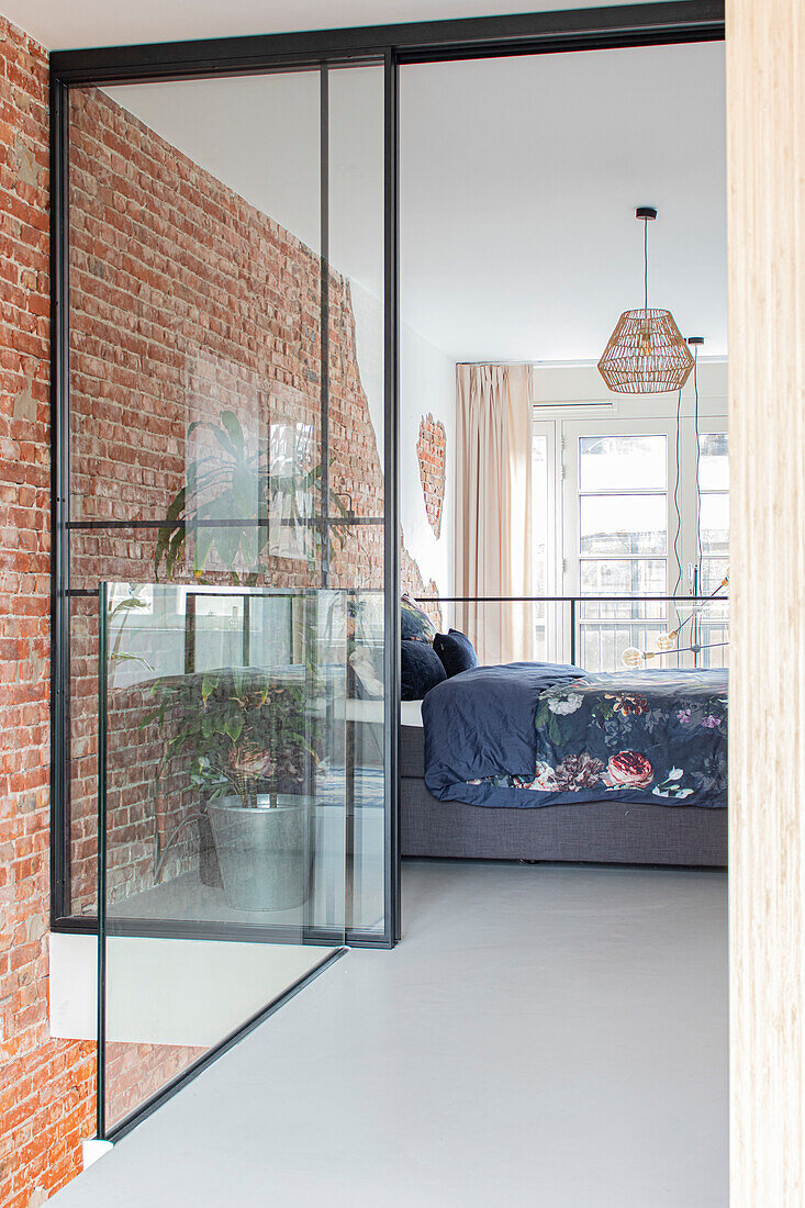 Bedroom with glass wall, brick wall and bed