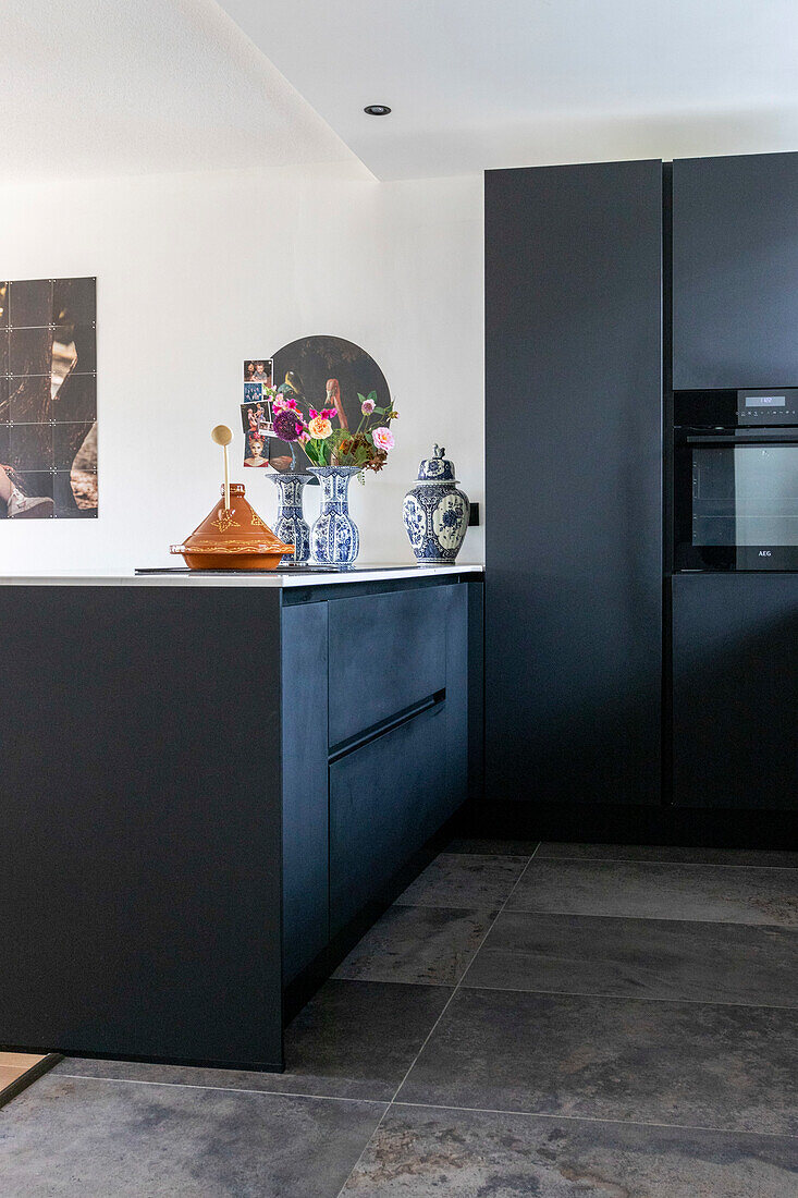 Modern kitchen with dark cupboards and decorative porcelain vases