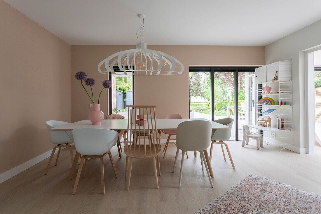 Dining area with white wooden table, large ceiling lamp and floor-to-ceiling windows