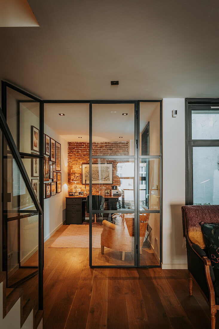 Blick durch Glastür im modernen Loftstil in Home Office vor Backsteinwand