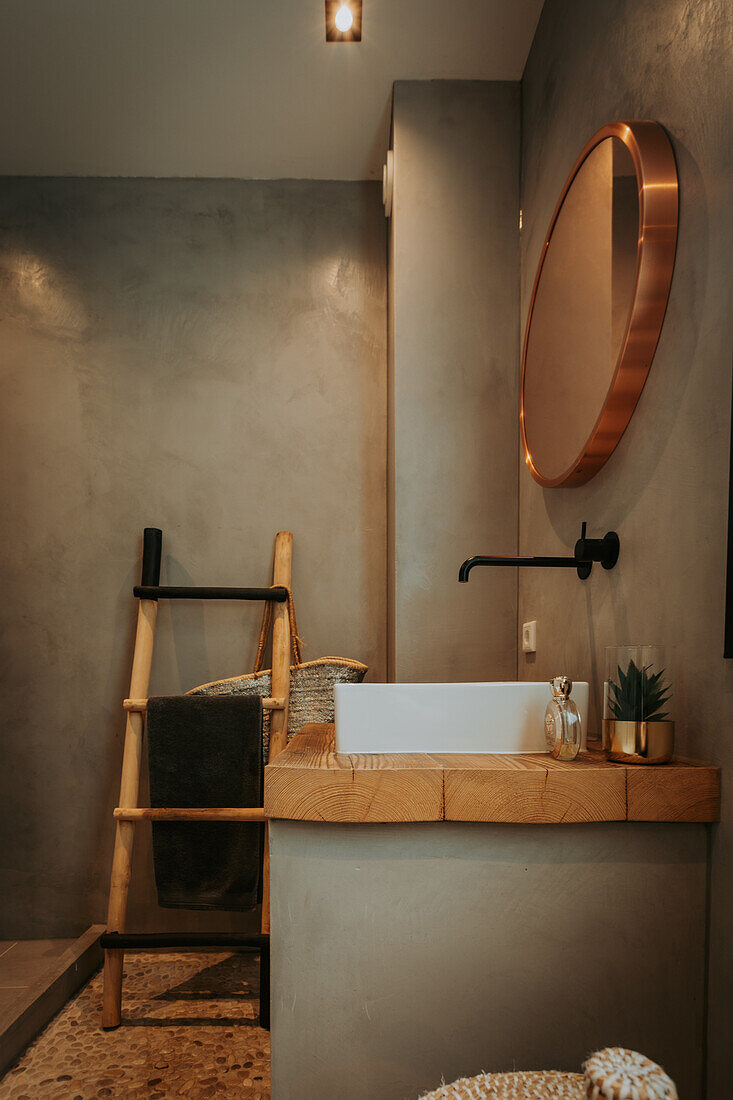 Modern bathroom with round copper mirror and bamboo ladder towel rail