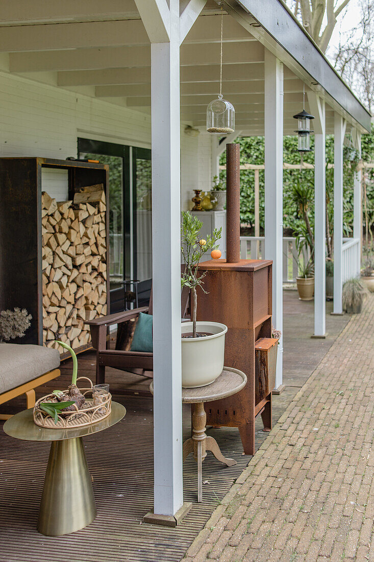 Überdachte Terrasse mit Holzlager, Holzmöbeln und Topfpflanzen