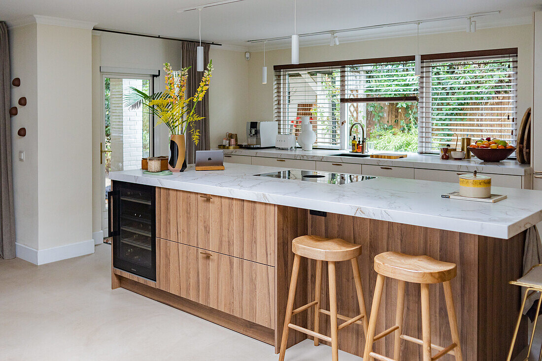 Modern kitchen with wooden island, white worktops and wooden bar stools