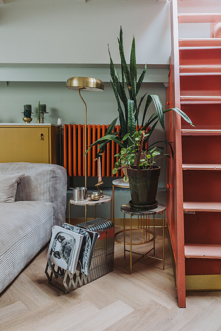 Staircase in coral red next to plants and side tables in the living room