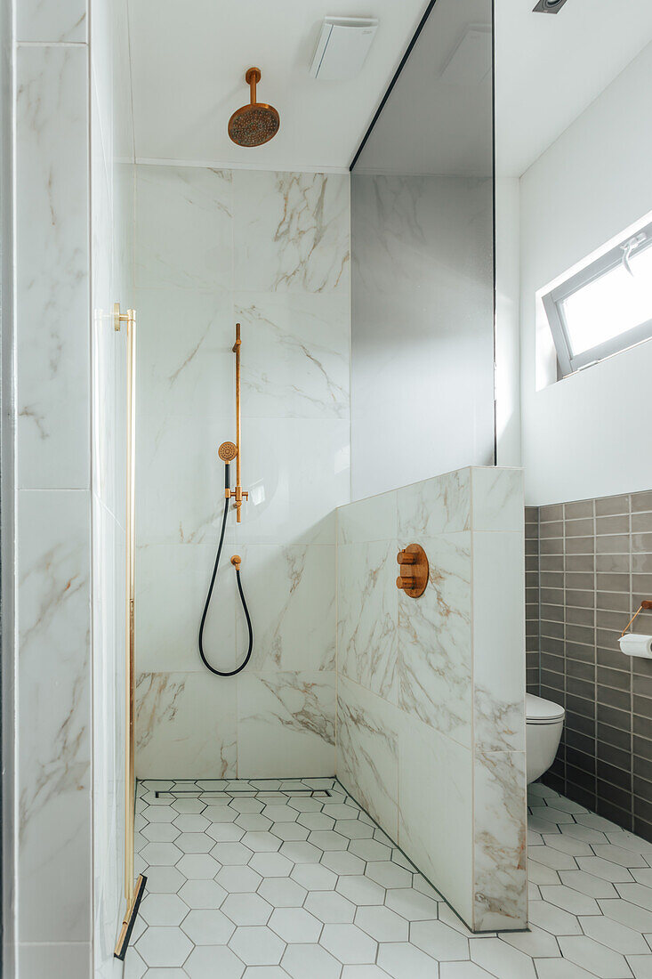 Modern bathroom with marble tiles, gold fittings and hexagonal floor tiles