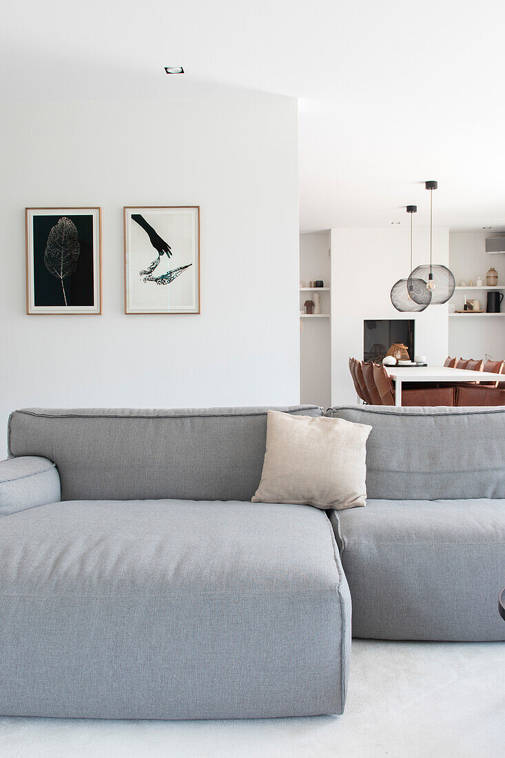 Hellgraues Sofa und moderner Essbereich mit Kunstwerken an der Wand