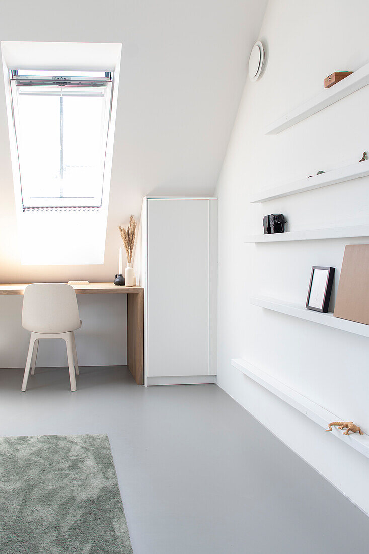 Helles Arbeitszimmer mit Dachfenster, minimalistischem Schreibtisch und weißen Wandregalen