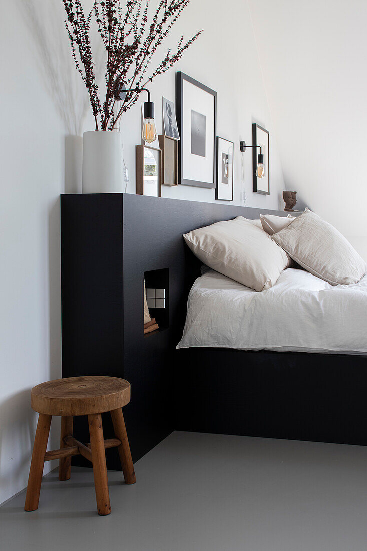 Minimalistisches Schlafzimmer mit schwarzem Bettrahmen und Holzhocker