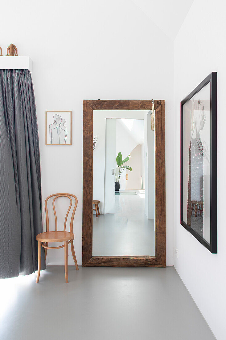 Large standing mirror with wooden frame and wooden chair in minimalist room