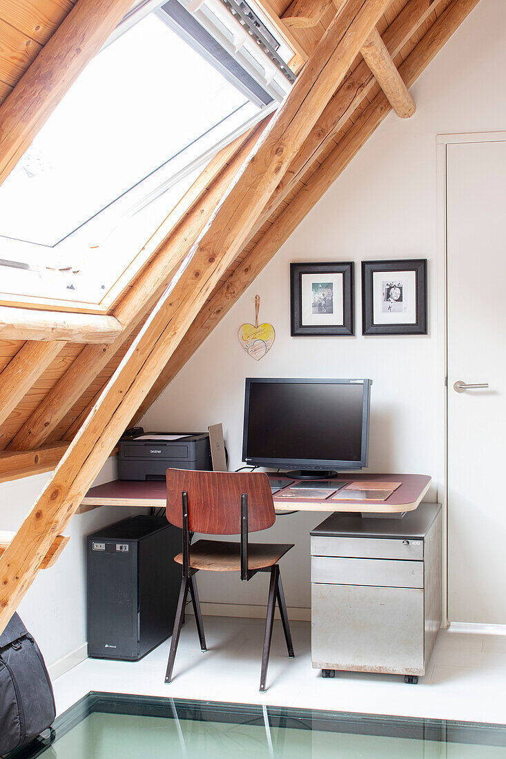 Arbeitsplatz unter Dachschräge mit Fenster, Schreibtisch und Stuhl