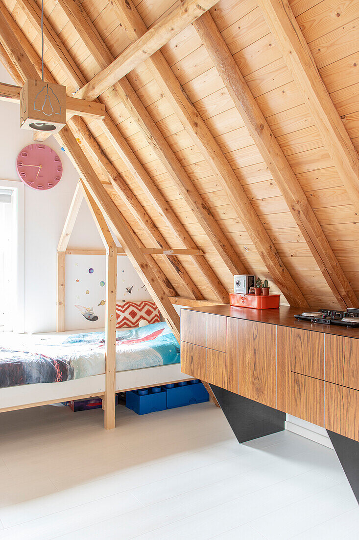 Wood-paneled attic ceiling bedroom with bed and sideboard