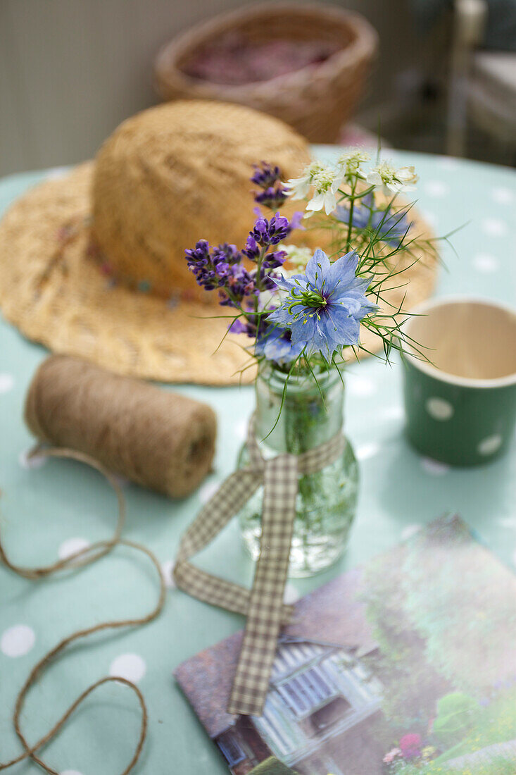 Sommerliche Tischdeko mit Lavendel und Strohhut auf gepunkteter Tischdecke