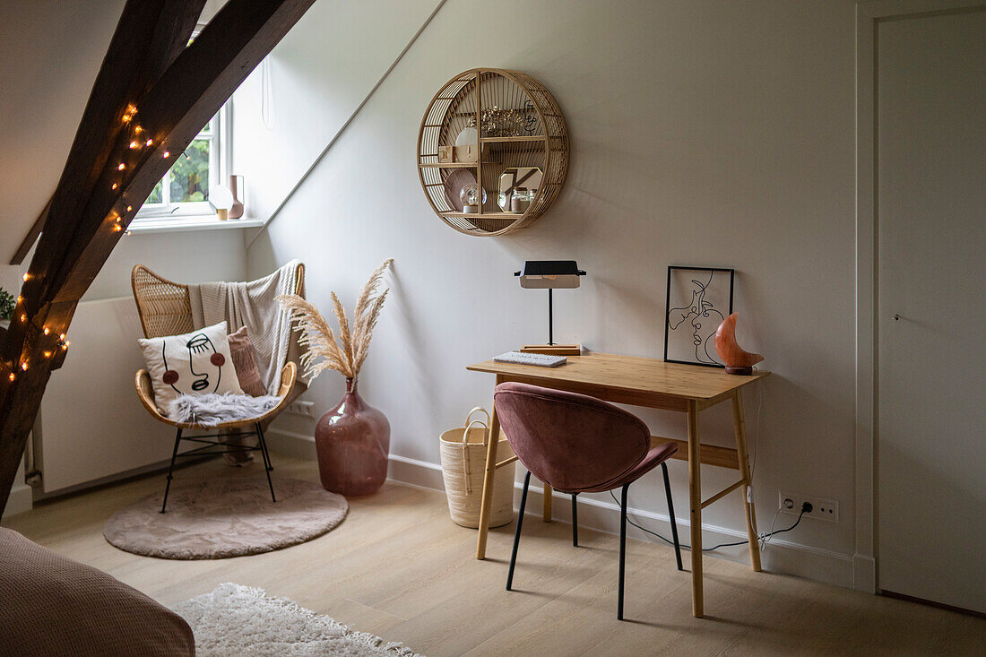 Work area with wooden desk and pink velvet chair in attic flat