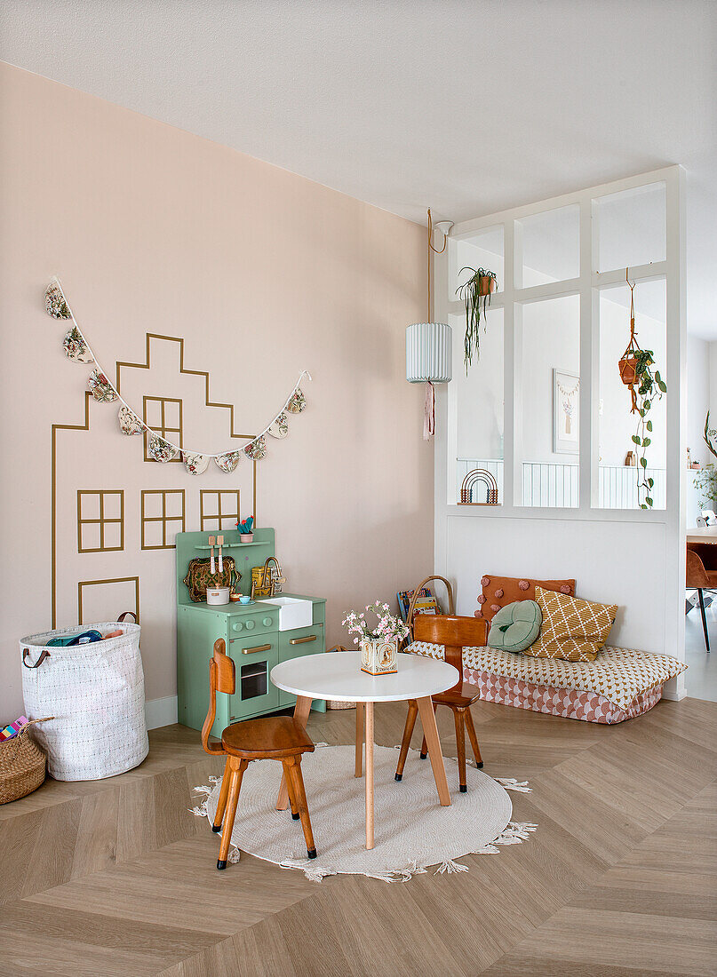 Children's room with play kitchen, round table, two chairs and decorative cushions