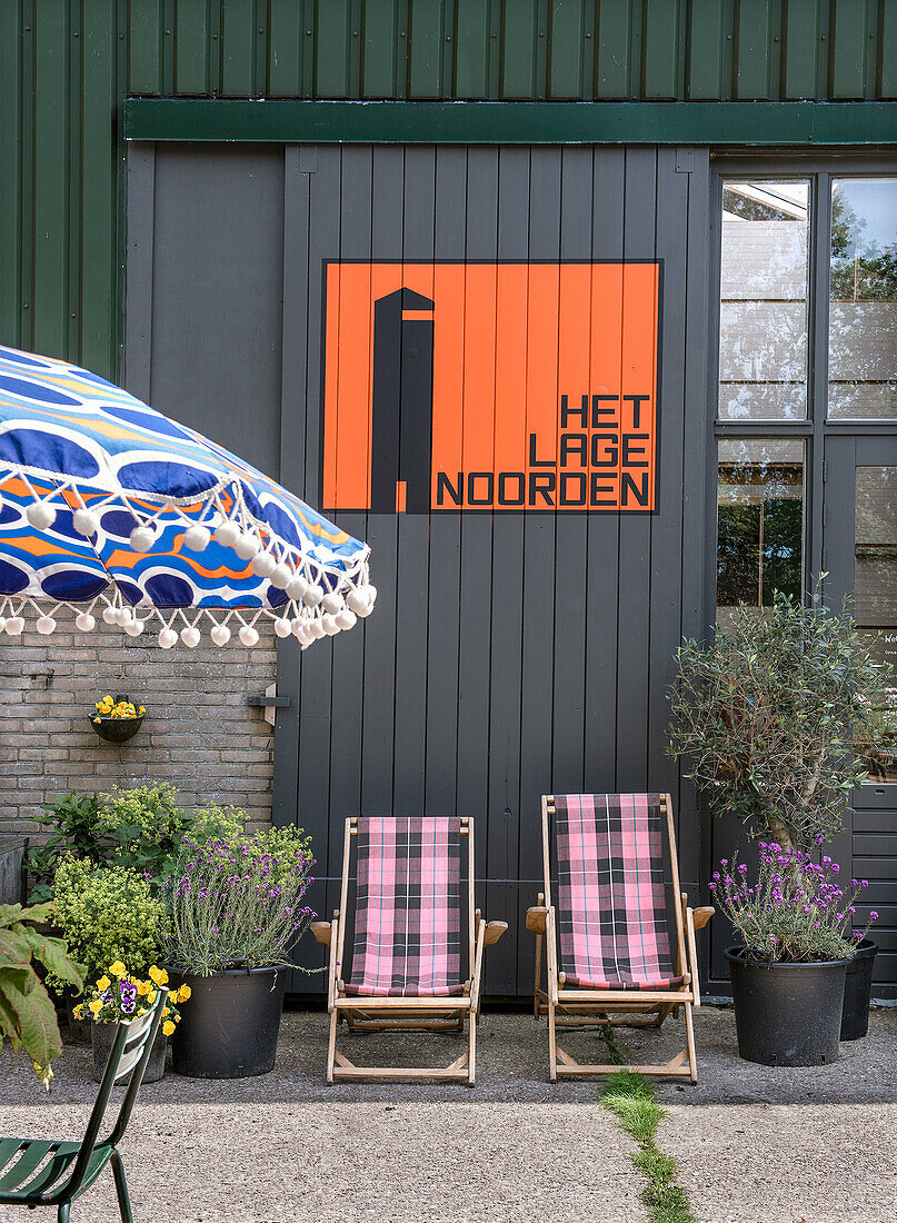 Deckchairs, plants and umbrella in front of a house