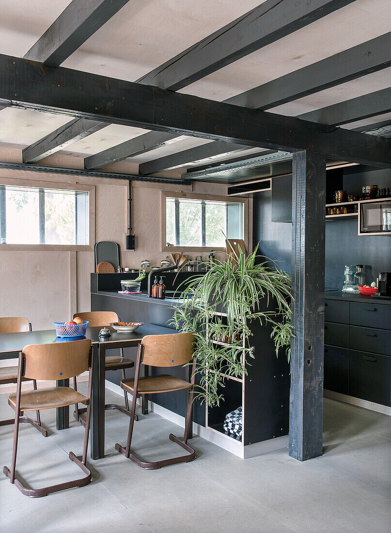 Dining area with wooden table and chairs in modern kitchen with black furnishings