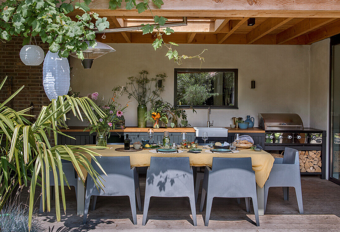 Überdachte Terrasse mit Esstisch und Grillbereich im Garten