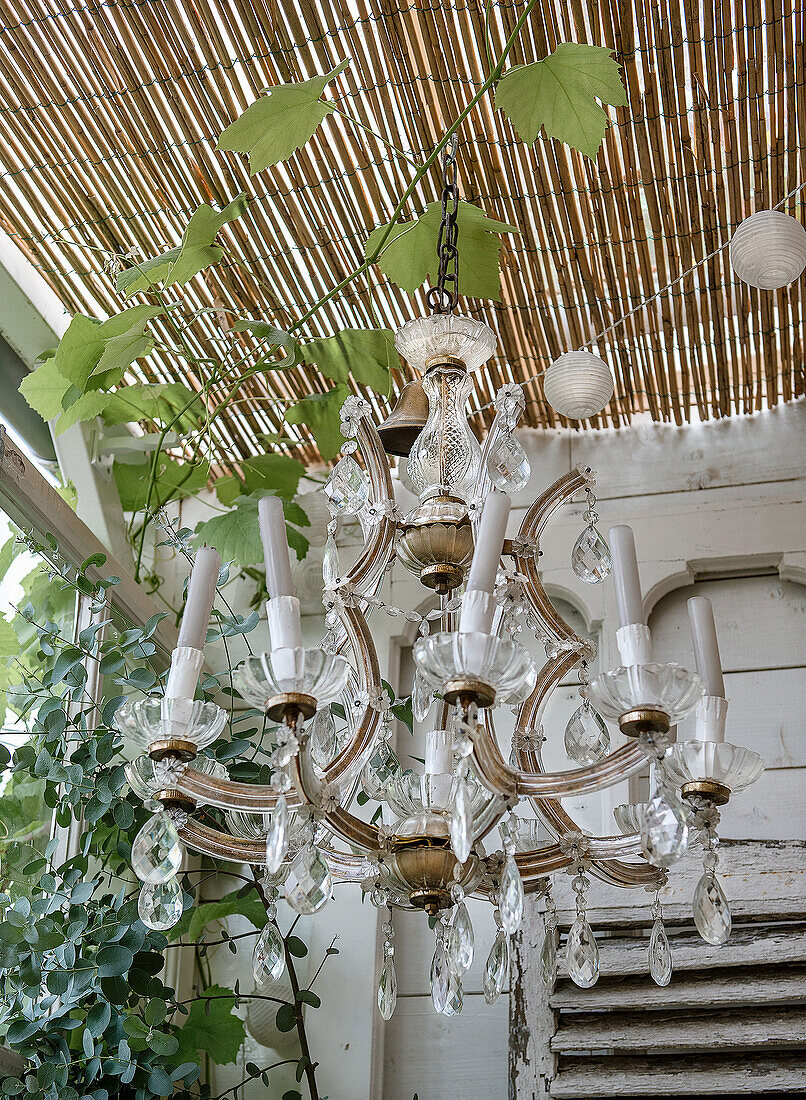 Crystal chandelier under a bamboo roof with ivy and fairy lights