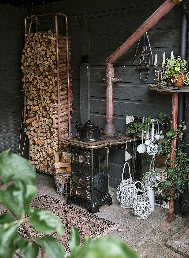 Pile of wood and antique stove in rustic corner with lanterns and plants