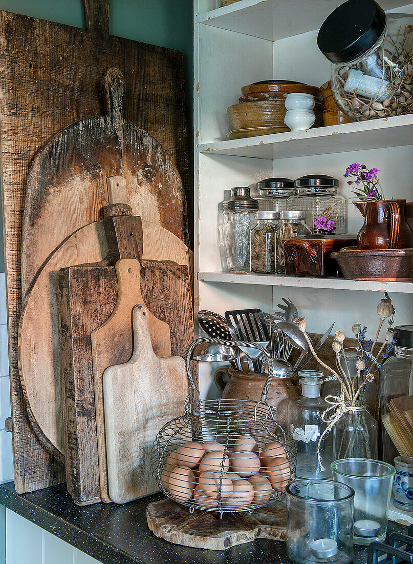 Rustic kitchen corner with wooden chopping boards and wire basket with eggs