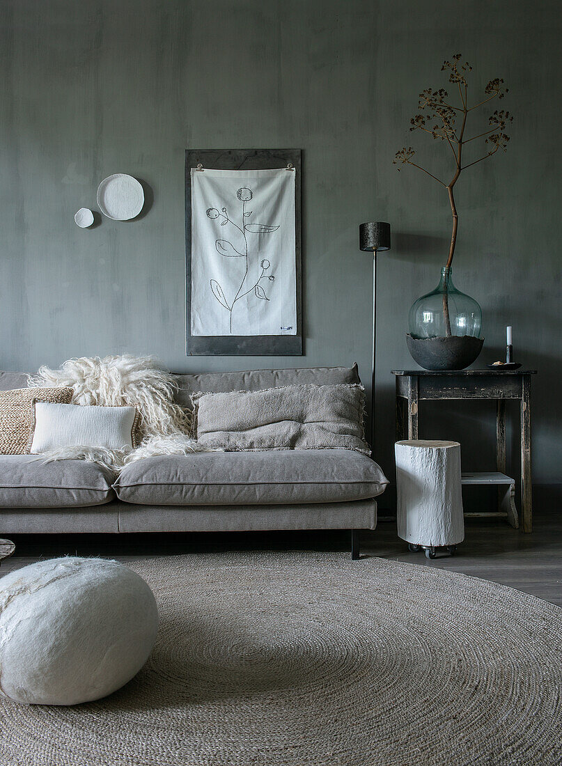 Living room with grey sofa, round jute rug and large glass vase