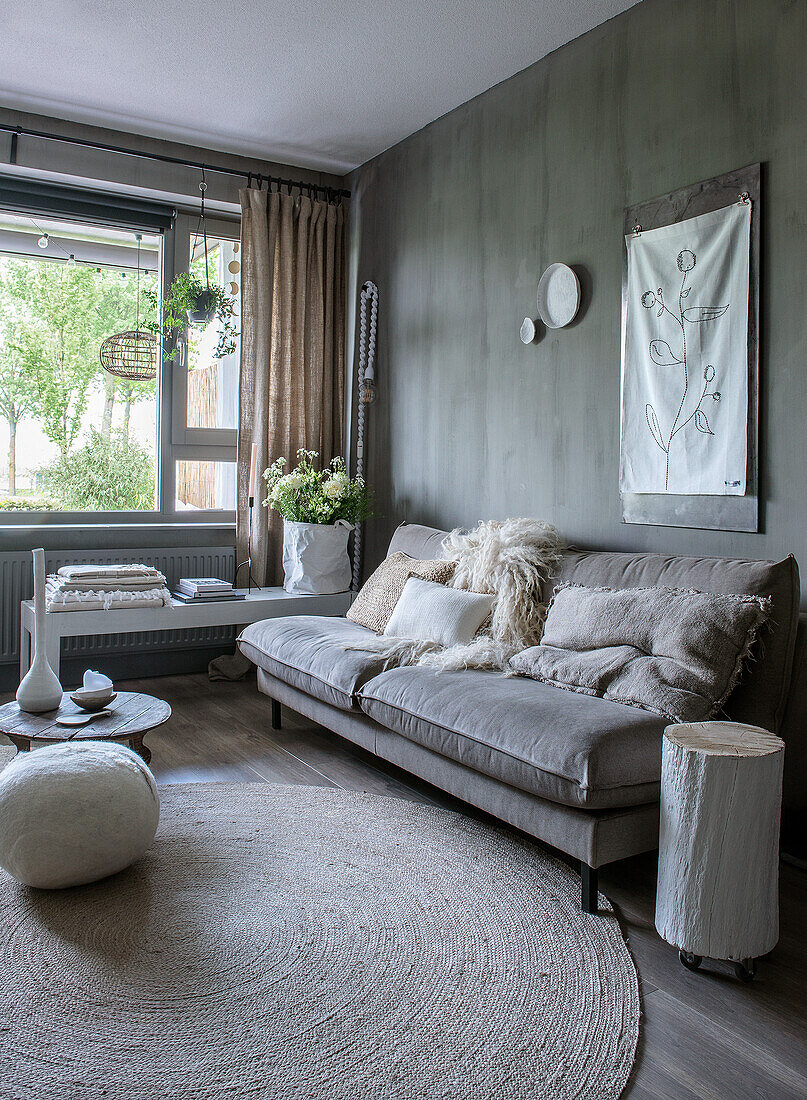 Living room with grey accent wall, grey sofa and light-colored textiles