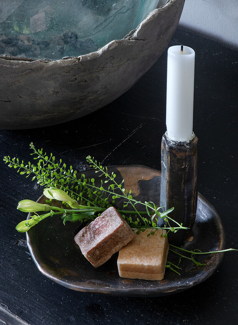 Soap bars and flower branches on candle holder with candle