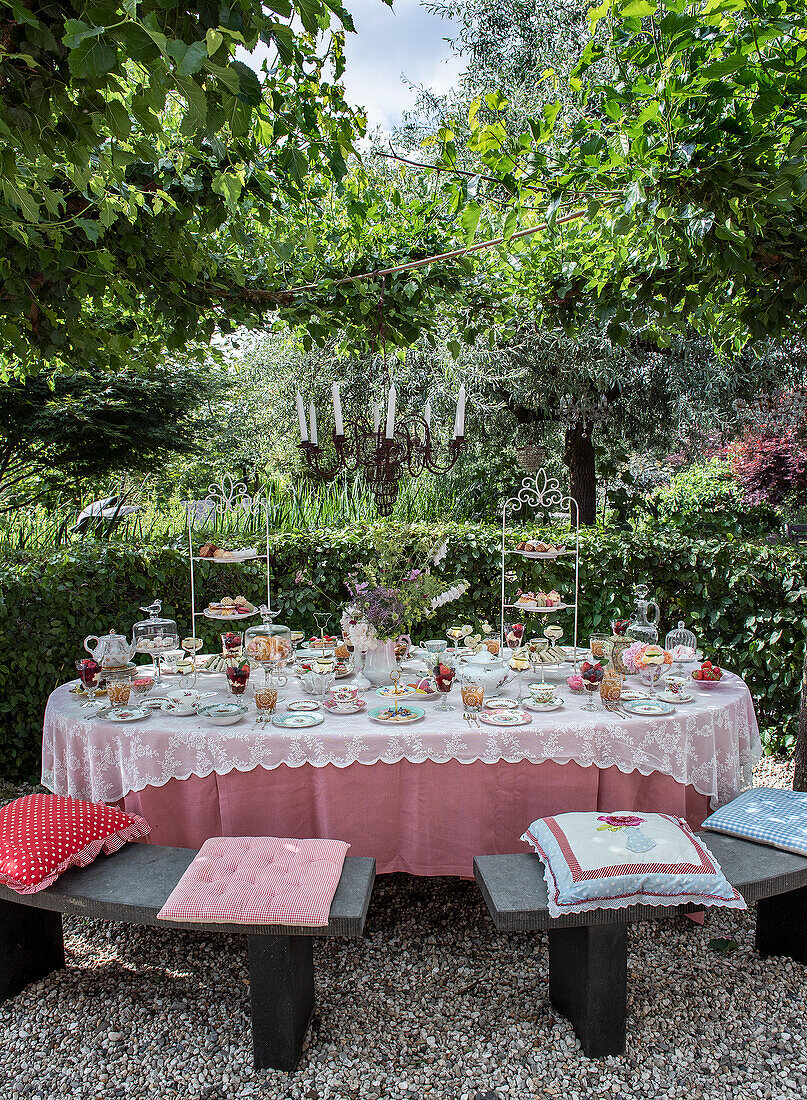 Festliche Kaffeetafel im Garten mit reich gedecktem Tisch und Kronleuchter