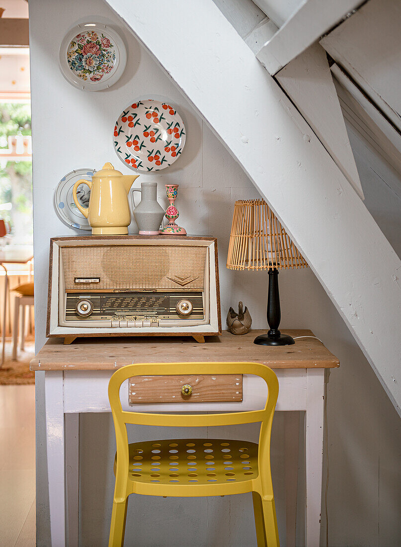 Vintage-Radio auf kleinem Tisch mit gelbem Stuhl unter Treppe