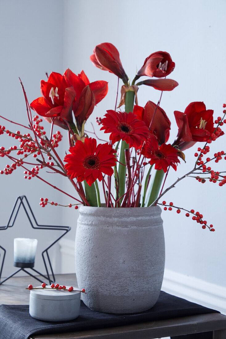 Strauß aus roten Blumen mitAmaryllis, rote Winterbeere (Ilex verticallata), Gerbera und Zweige von rotem Hartriegel