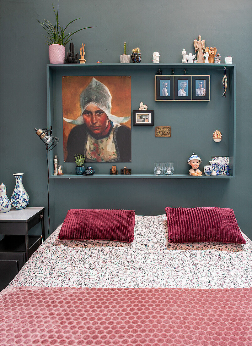 Bedroom with framed pictures and red cushions on bed with patterned bed linen