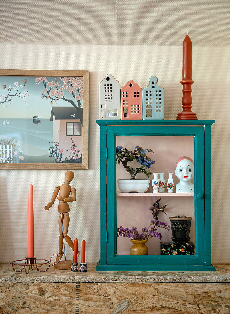 Display cabinet with decorative figurines and plants, retro picture and candlestick