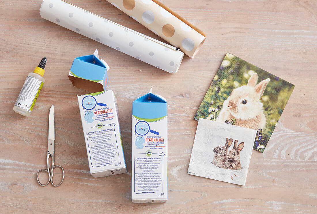 DIY decoration: Milk cartons, scissors, glue and bunny motif templates on wooden table