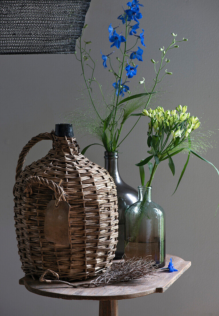 Wicker basket bottle and flower vases on wooden table