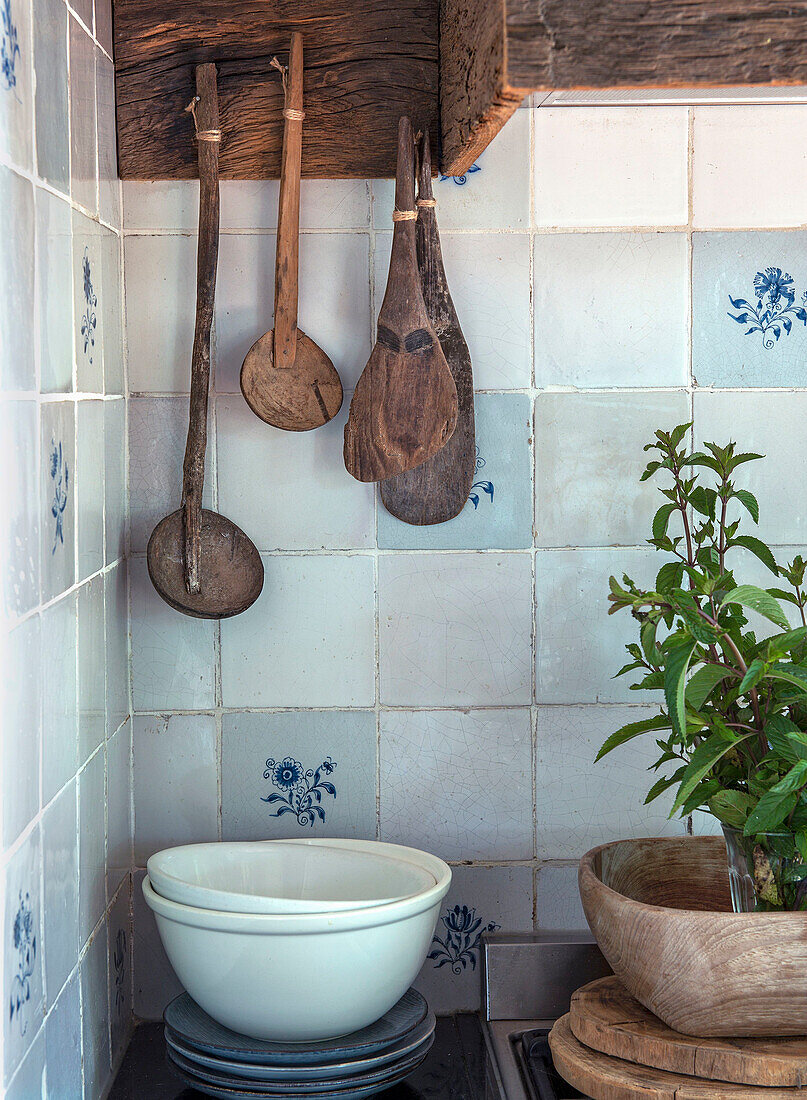 Antique wooden spoons and bowls in rustic kitchen unit with tiled backsplash