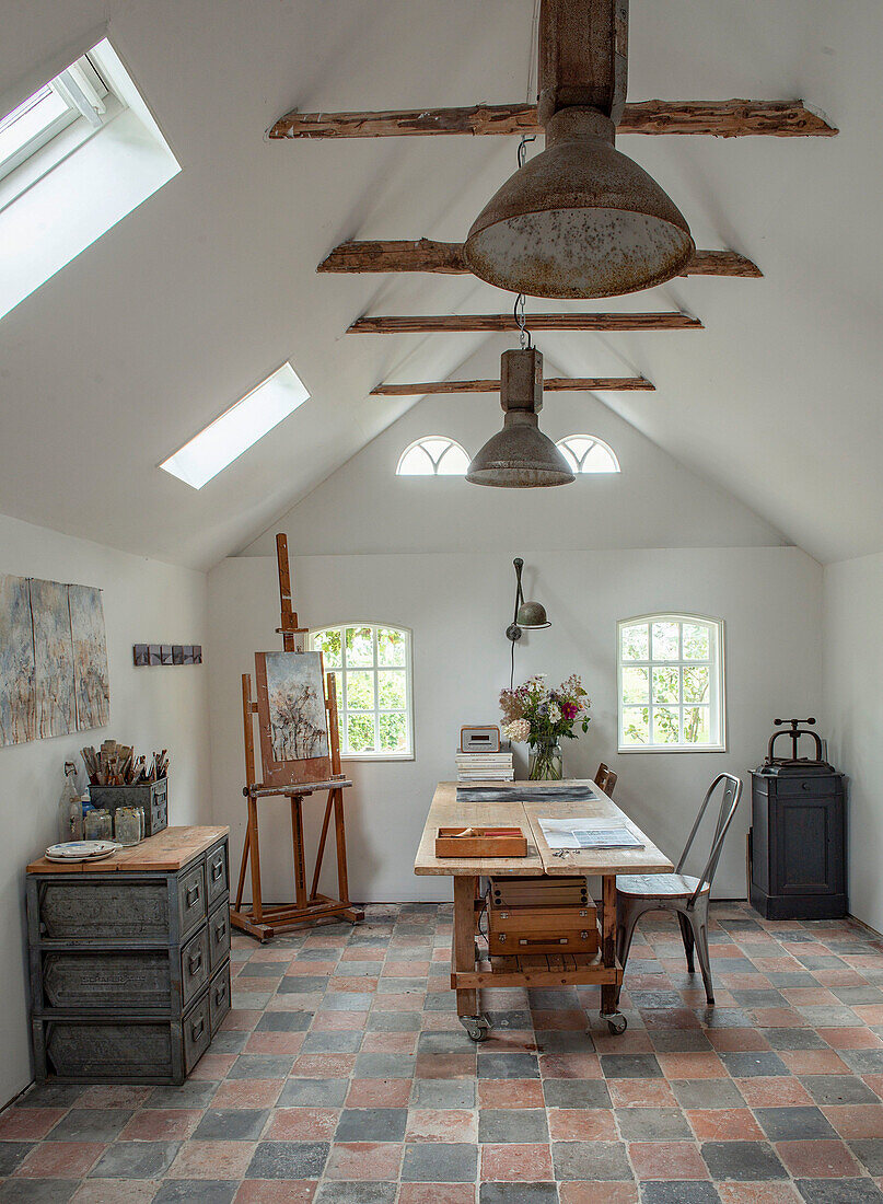 Artist's studio with easel, wooden table and skylights