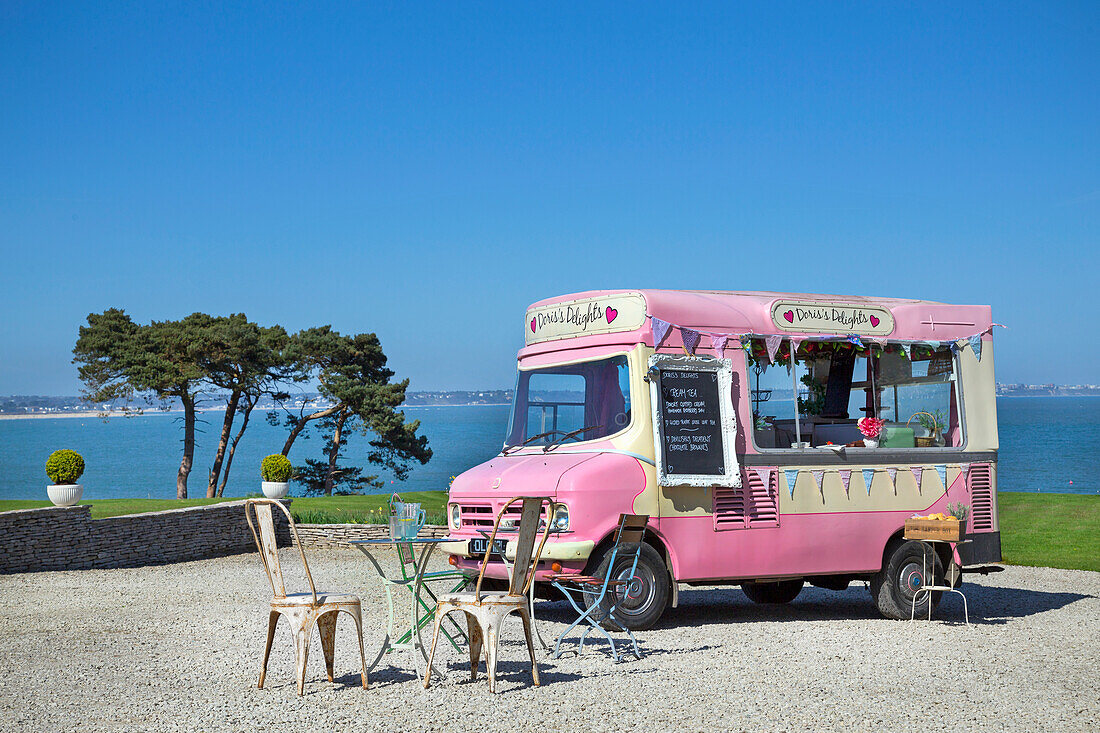 Vintage-style ice cream van with small seating area on the coast