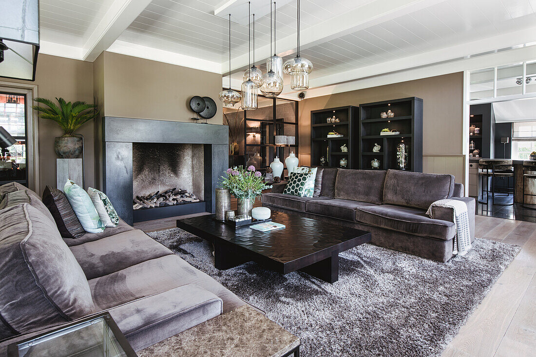 Spacious living room with fireplace, grey leather sofas and dark shelves