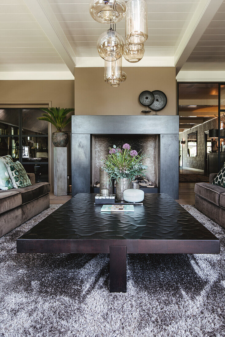 Dark living room with fireplace and solid coffee table on a deep-pile carpet