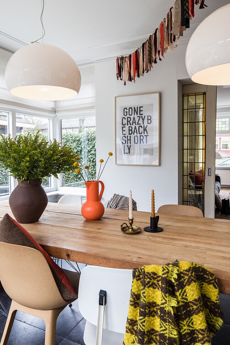 Dining table with light wooden top, colourful woollen plaid and modern pendant lights