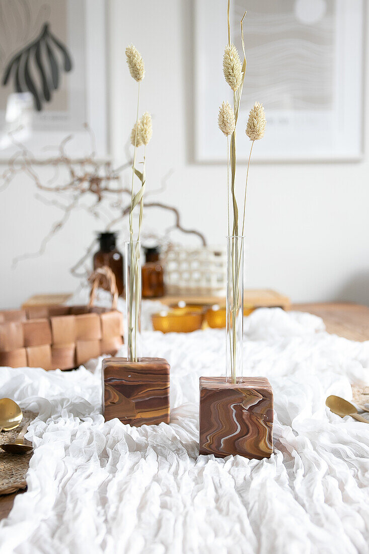 Decorative table with dried grasses in marble cube vessels