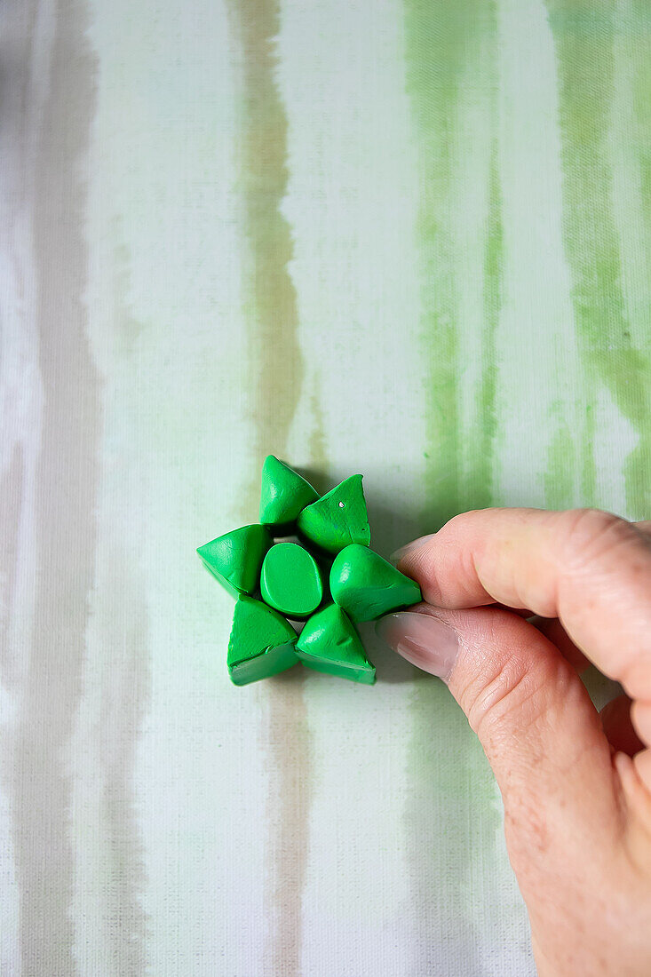 DIY decoration made from green modeling clay in the shape of a star on a striped background